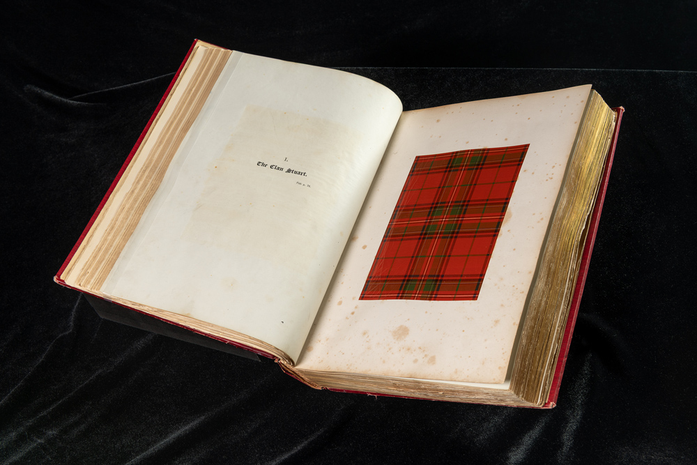 An open book showing a sample of red and green tartan cloth.