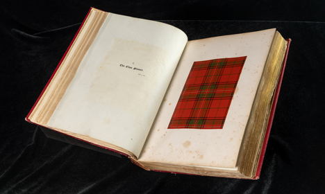 An open book showing a sample of red and green tartan cloth.