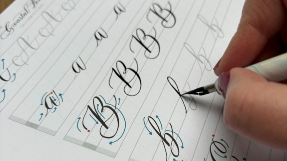 A person practising calligraphy letters.