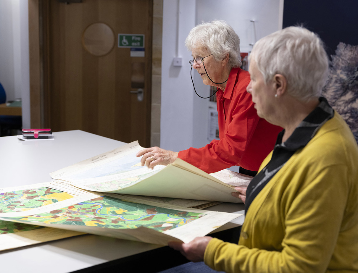 Two adults standing at a table looking at maps.